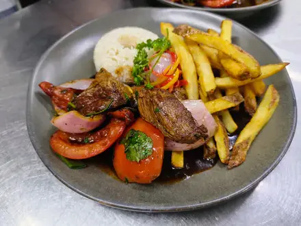 Filete saltado con cebolla morada, tomate y papas fritas, acompañado de arroz blanco
