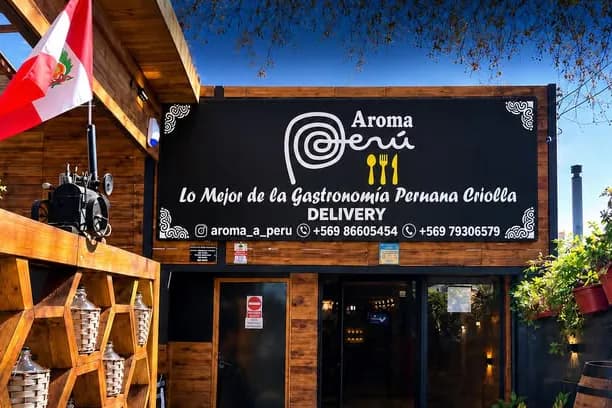Fachada de madera de Aroma Perú en Avenida Rosario 171, con el letrero y el estante de botellas de pisco